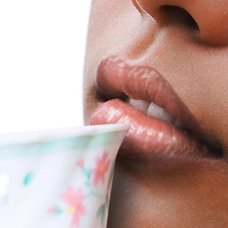 Nahaufnahme von Lippen, die an einer Tasse mit Blumenmuster nippen.